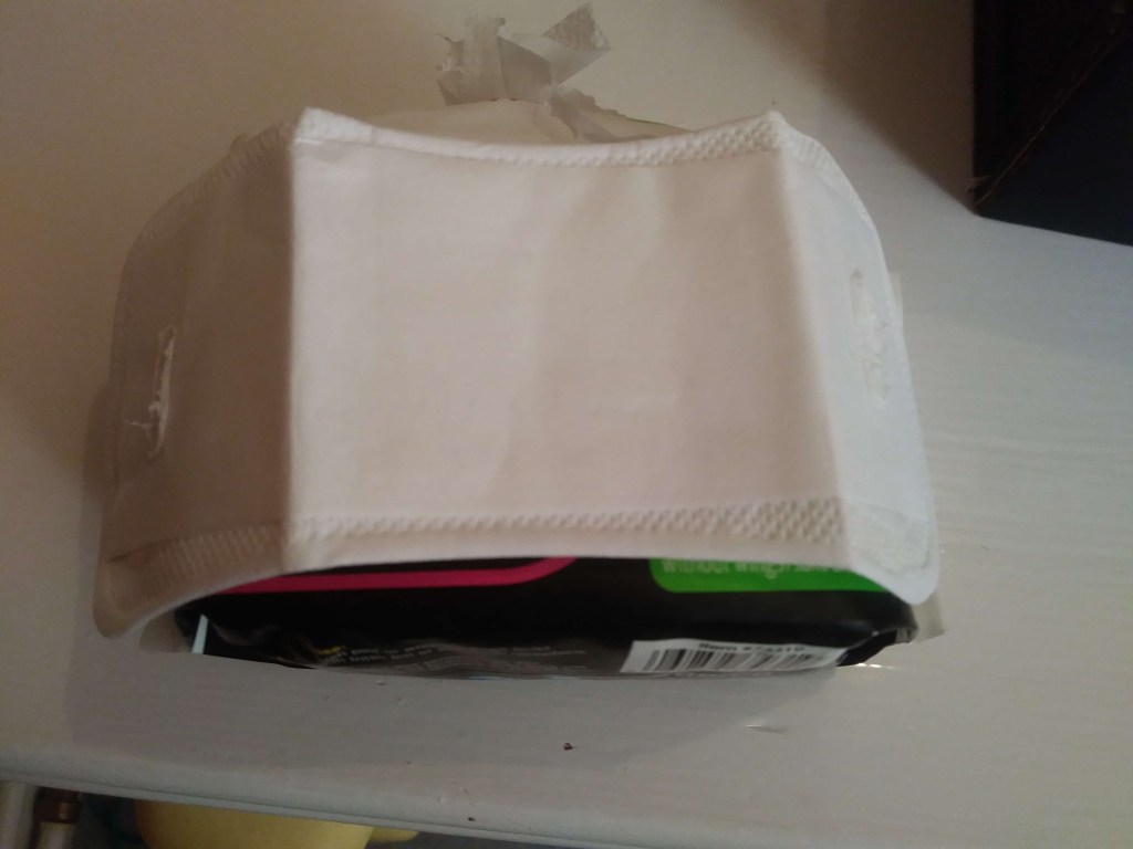 Small, white, unwrapped Bodico panty liner, with the plastic paper strip on the back. It's displayed lengthways. 