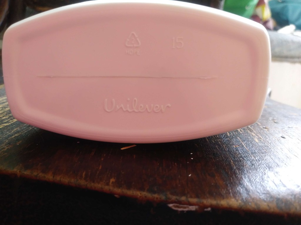 Bottom of the St. Ives bottle. White, with raised engravings of a recyclable symbol on it, the number 15, and the name Unilever.